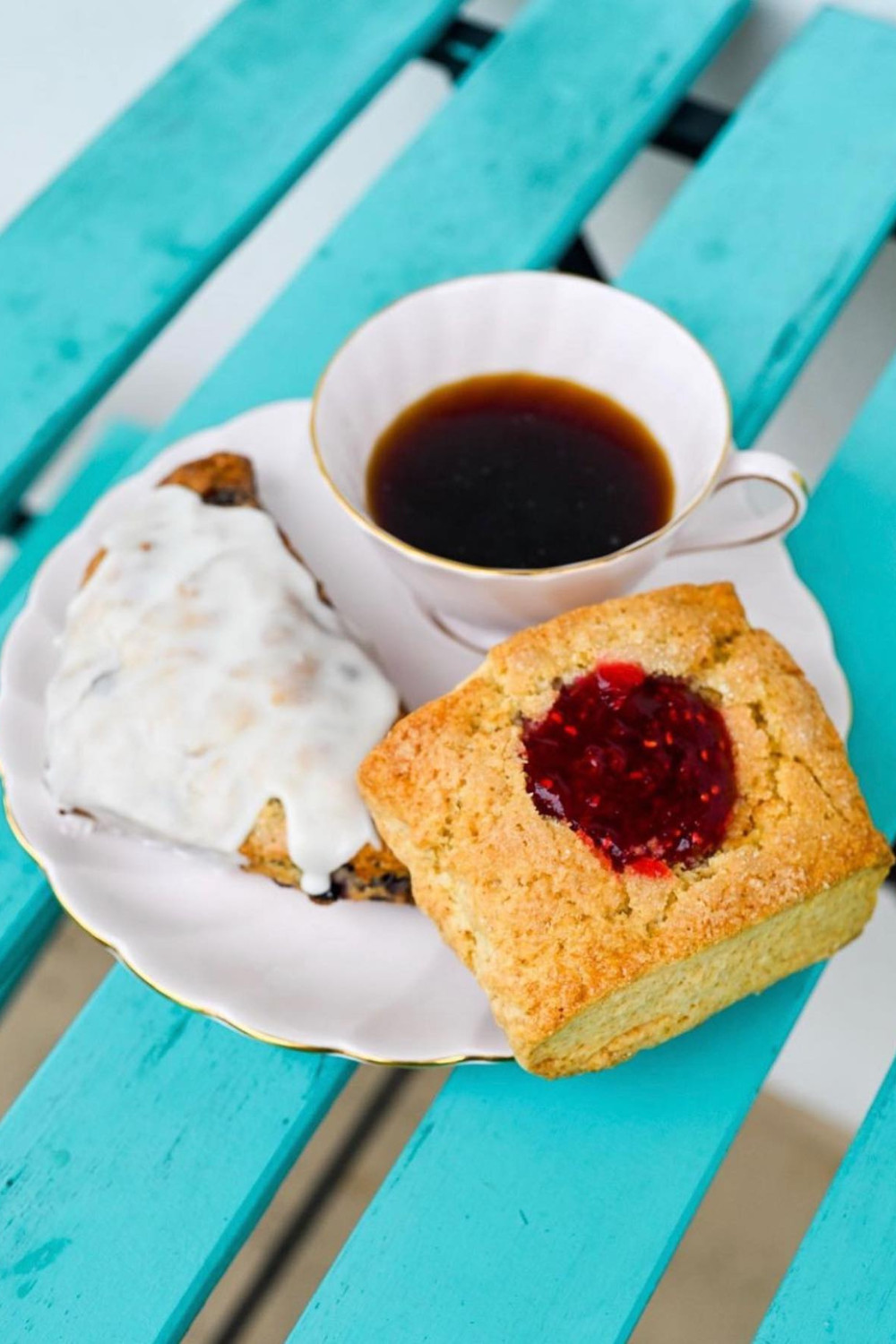 a plate with a cup of coffee and two pastries on a blue wooden table